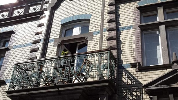 A multi-story building with a distinctive architectural style, featuring a balcony with ornate metal railings and a window with a decorative arch. - B&B Villa D'Hondt (Blankenberge)