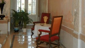 A grand hallway with a high ceiling, a large window, and a table with chairs. - B&B Villa D'Hondt (Blankenberge)