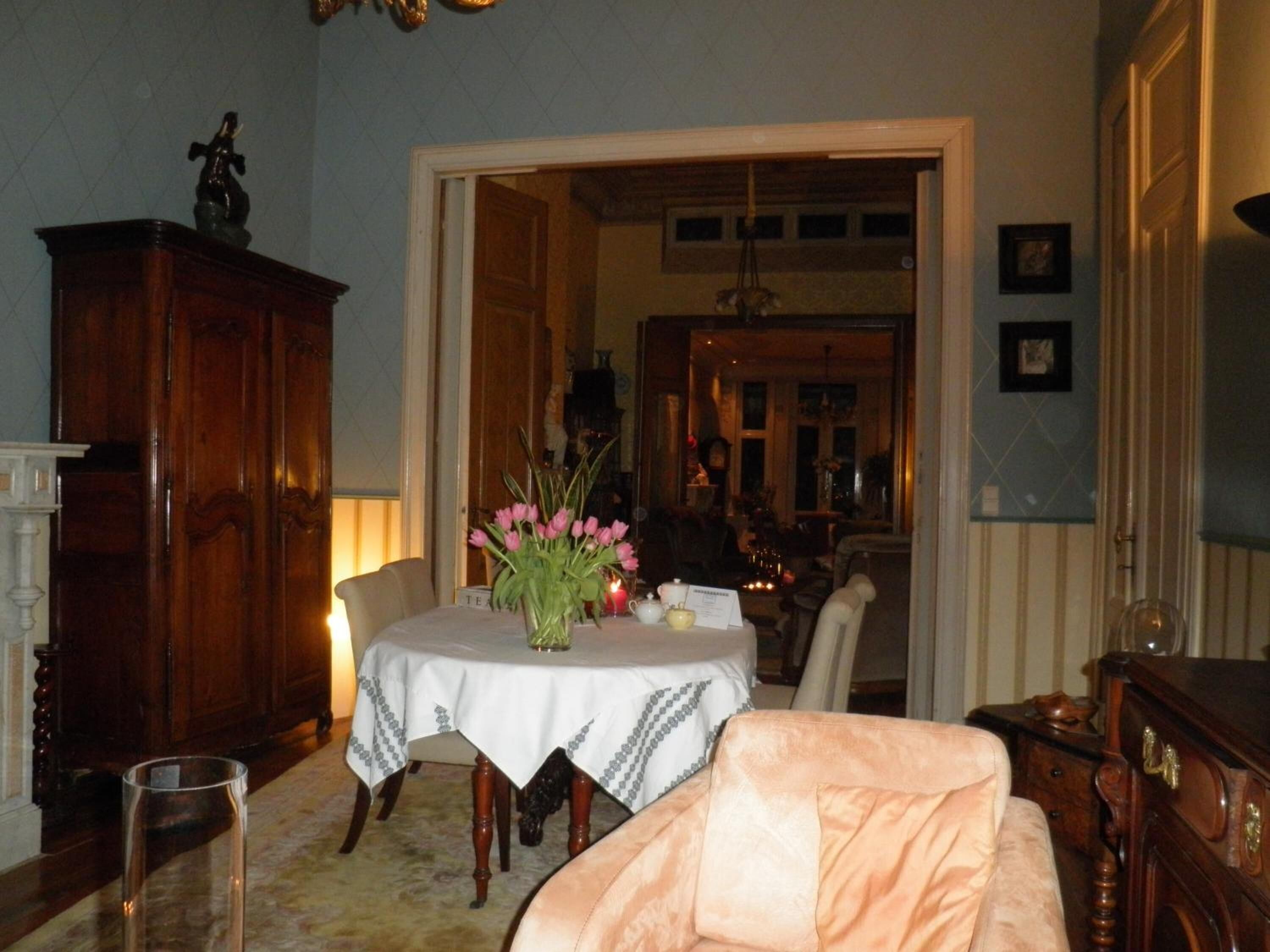 Uma área de refeições com mesa posta para dois, um armário de madeira e uma cadeira.