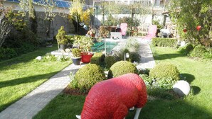 A garden with a large sheep sculpture, potted plants, and a pathway. - B&B Villa D'Hondt (Blankenberge)