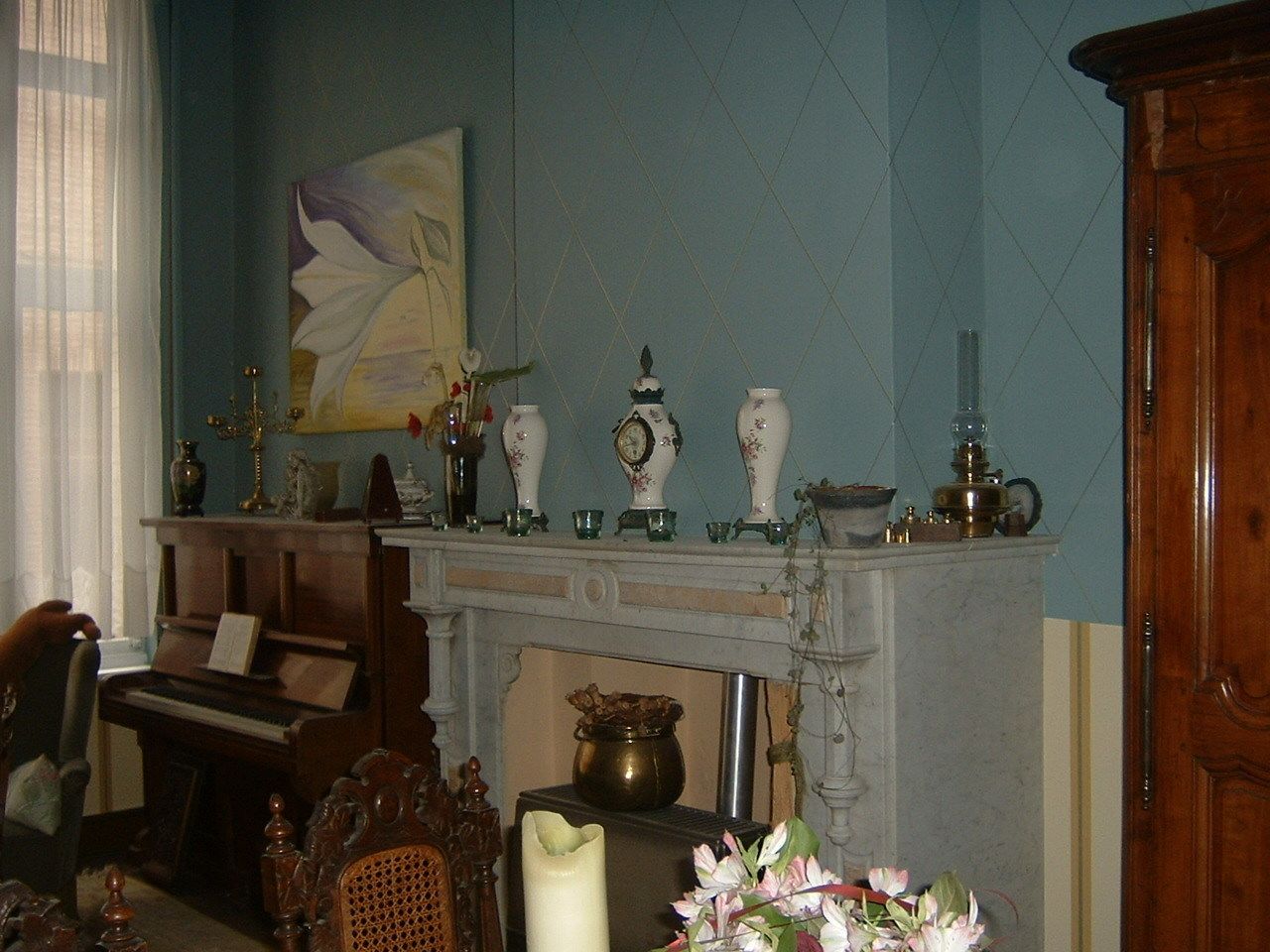 Una habitación con un piano, una chimenea y varios objetos decorativos en la repisa.