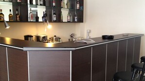 A bar area with a counter, a coffee machine, a lamp, and a shelf with bottles. - Porto Marathos (Trifylia)