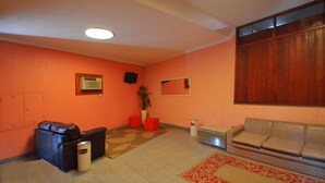 A room with orange walls, a brown carpet, a beige sofa, a black leather couch, and a wooden partition. - Verona Hotel - Adults Only (Rio de Janeiro)