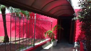 A corridor with a red brick wall, a metal fence, and a potted plant. - Verona Hotel - Adults Only (Rio de Janeiro)
