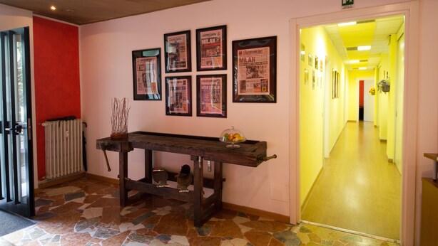 A hallway with a stone floor, a wooden bench, and framed posters on the wall. - Luci a San Siro (Milan)