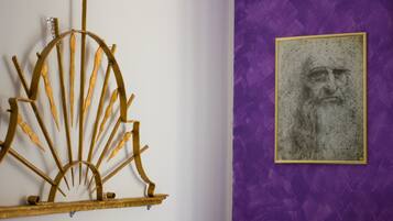 Una pared con una escultura de metal y una obra de arte enmarcada.