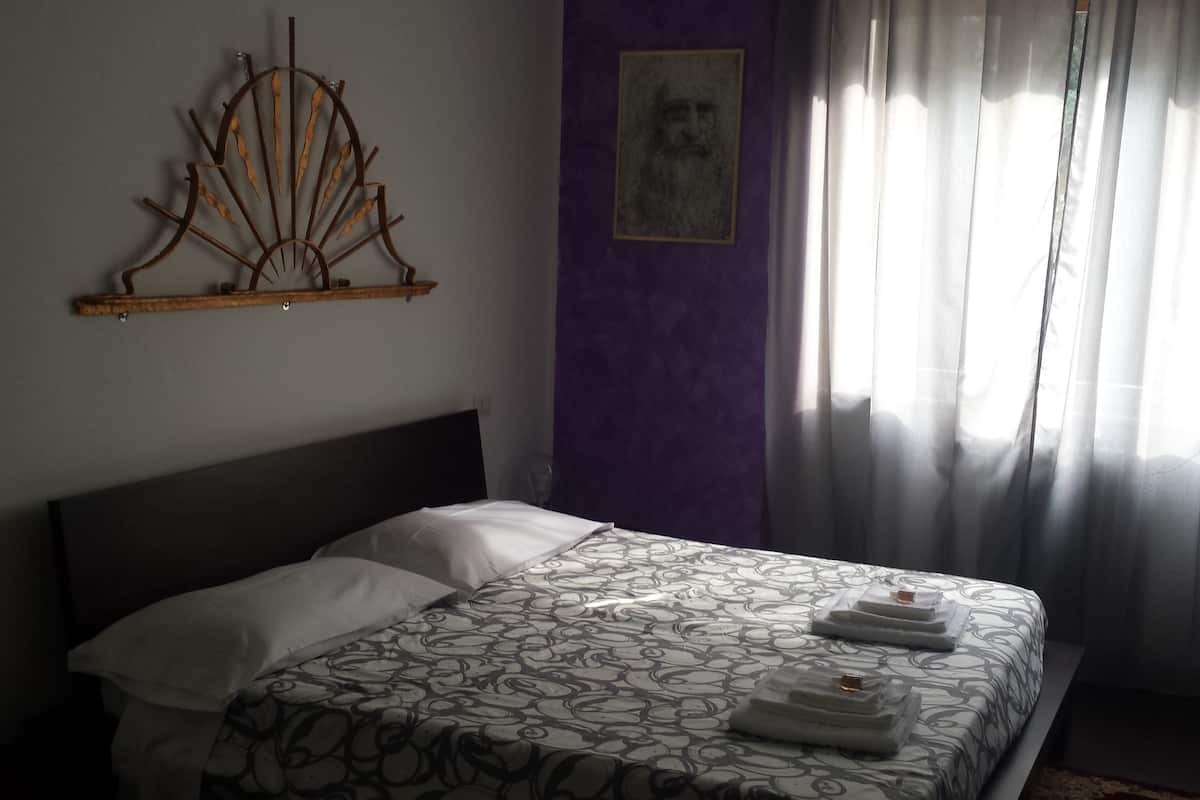 Un dormitorio con una cama, un adorno en la pared y una ventana con cortinas.