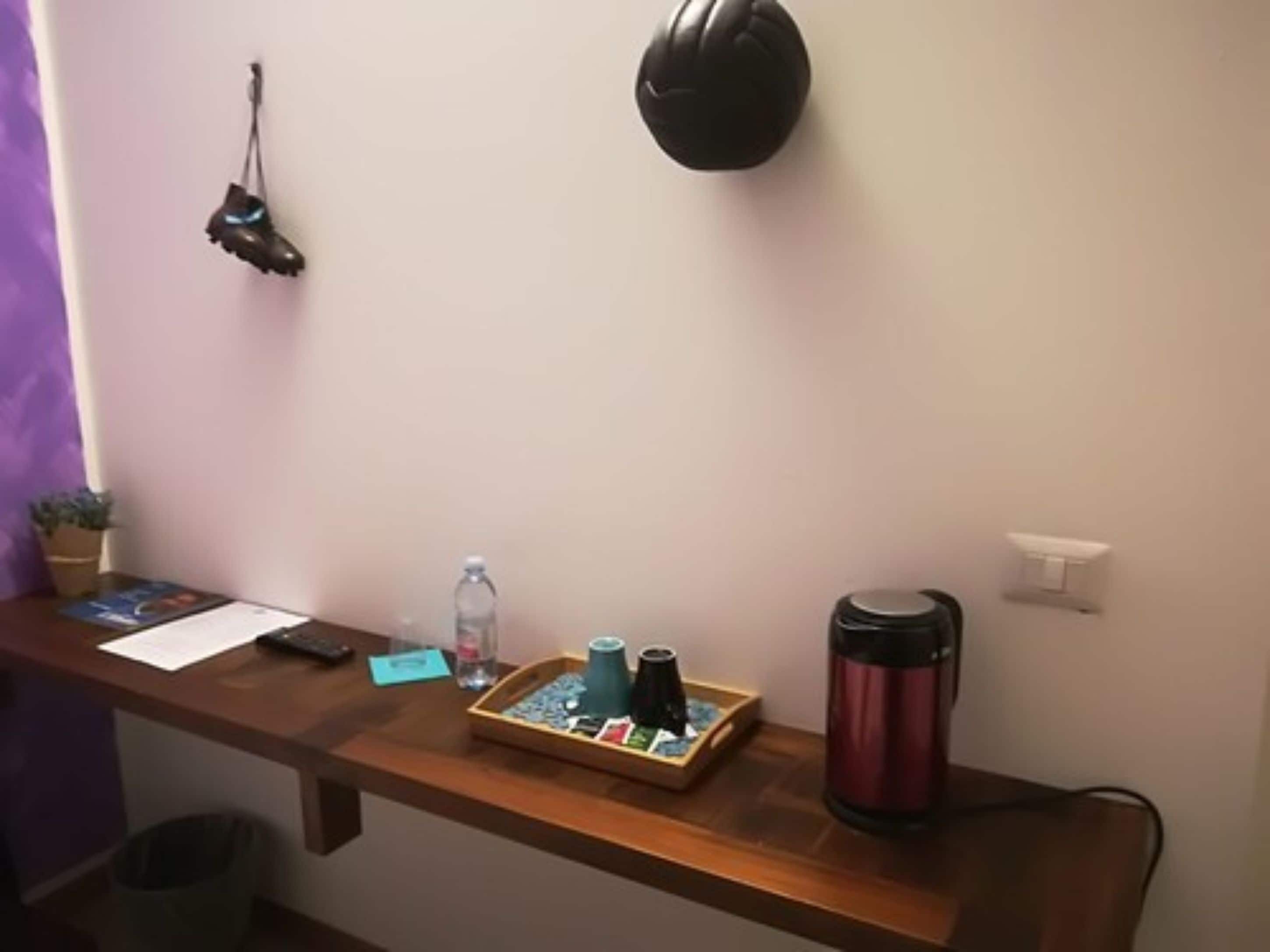 A wooden desk with a laptop, a water bottle, a thermos, and a small plant.
