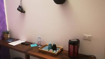 A wooden desk with a laptop, a water bottle, a thermos, and a small plant.