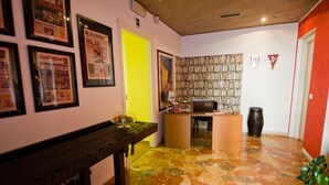 A room with a wooden bench, a desk with a computer, a bookshelf, and a tiled floor. - Luci a San Siro (Milan)