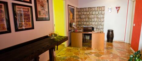 A room with a wooden bench, a desk with a computer, a bookshelf, and a tiled floor.