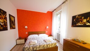 A bedroom with a large bed, a wooden dresser, and two wall-mounted lamps. - Luci a San Siro (Milan)