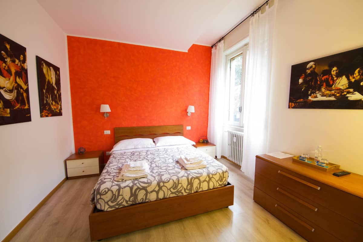 Un dormitorio con una cama grande, un aparador de madera y dos lámparas de pared.