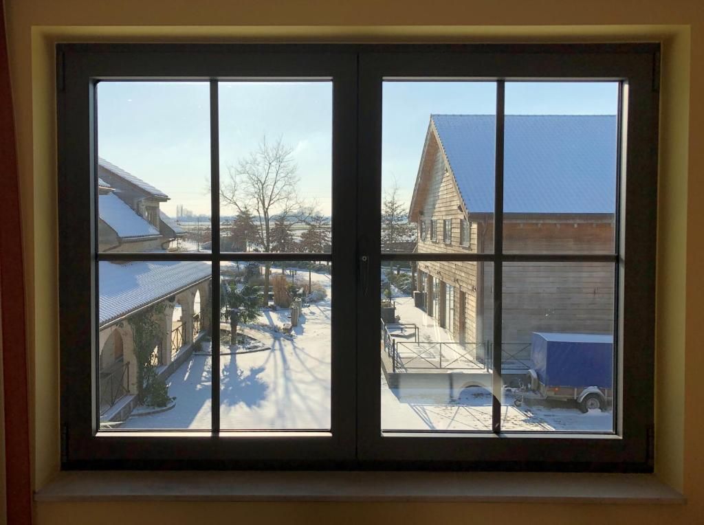 Una ventana con vista a un edificio de techo azul y suelo cubierto de nieve.