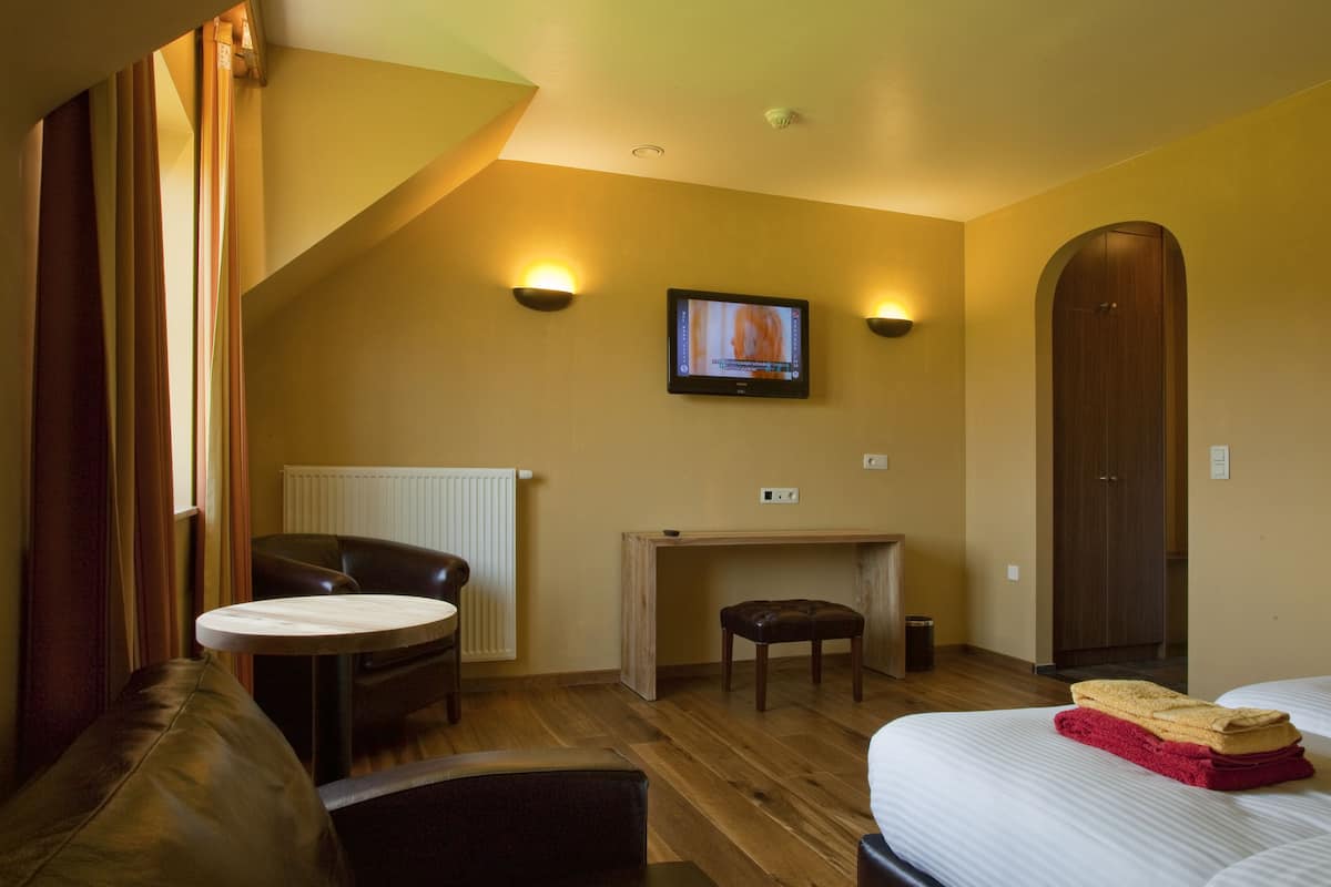 Ett hotellrum med en säng, ett skrivbord, en stol, en tv och en garderob.