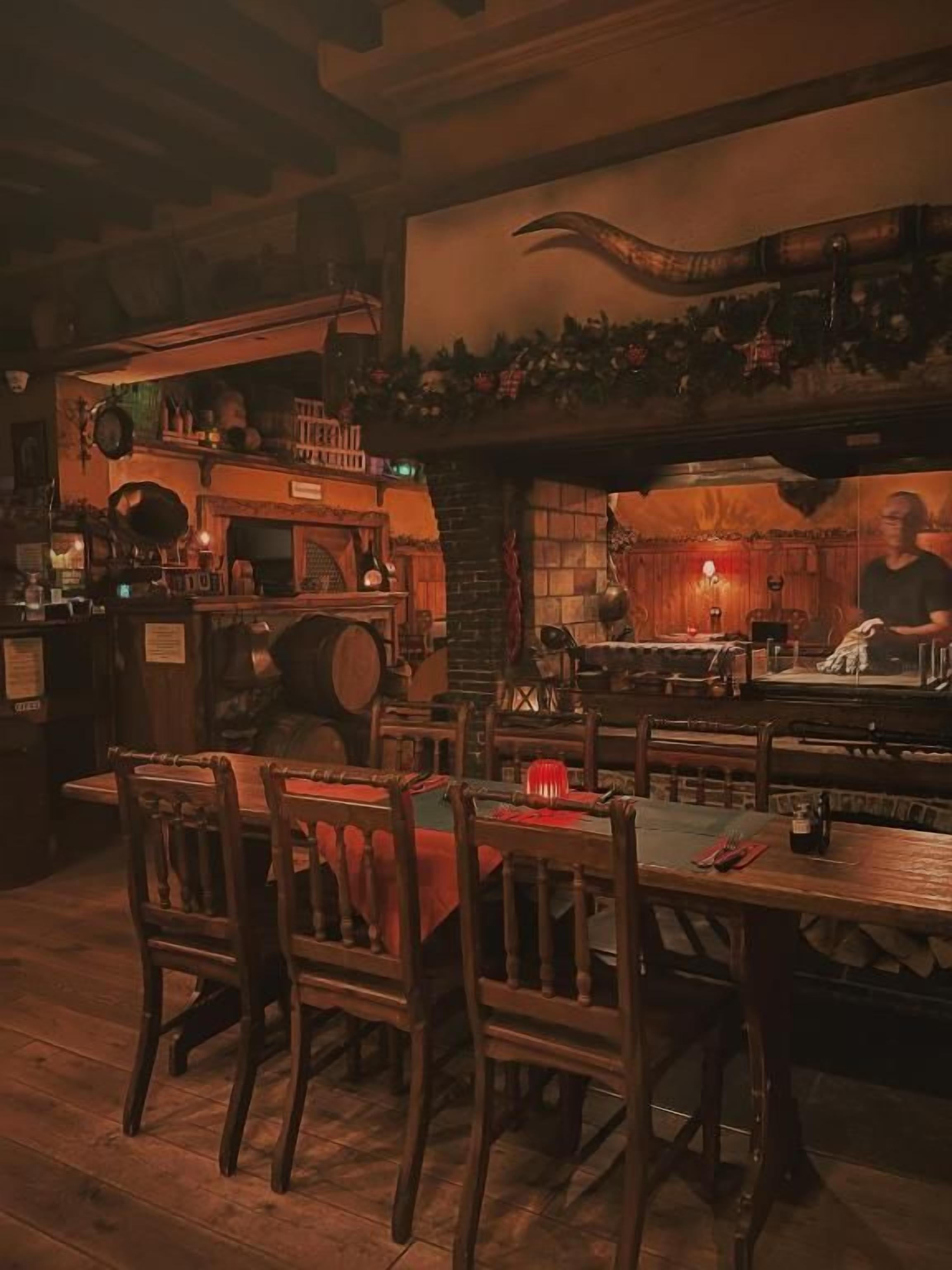 A dimly lit bar area with wooden furniture and a mural on the wall.