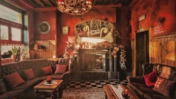 A cozy room with a fireplace, leather sofas, a patterned rug, and a chandelier.