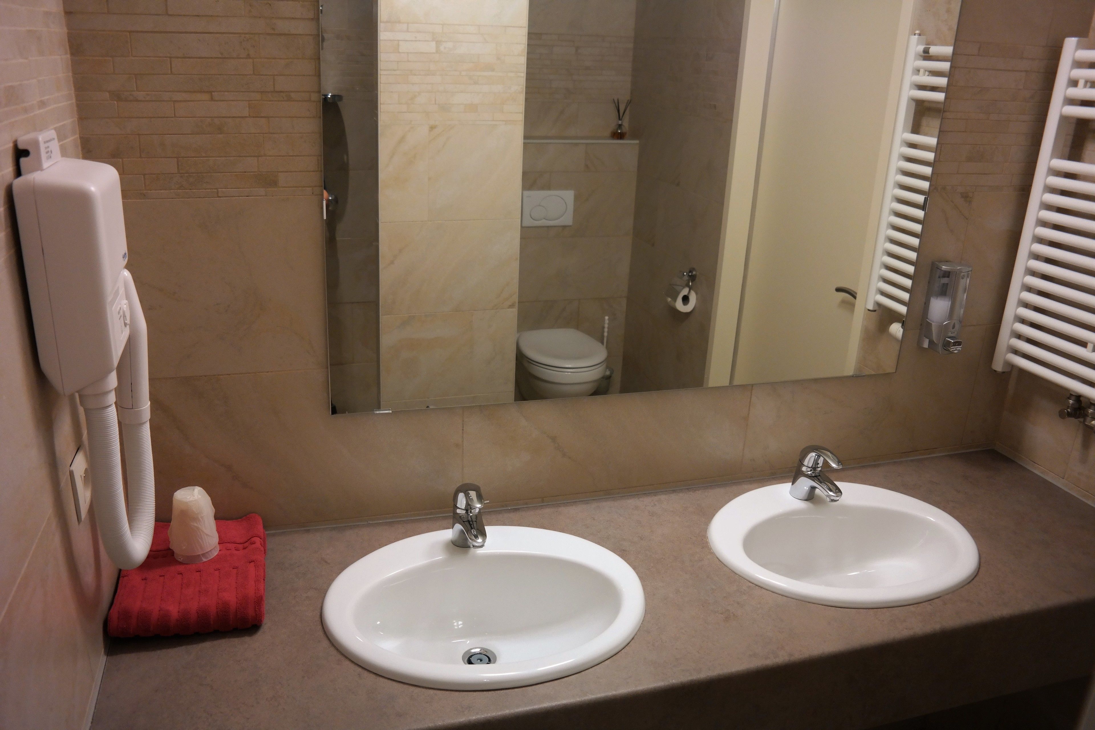 A bathroom with two sinks, a mirror, and a towel rack.