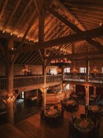 Un interior de madera con varios niveles, mesas, sillas, un balcón y una chimenea.