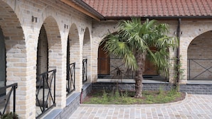 A courtyard with stone arches, a palm tree, and a tiled roof.
