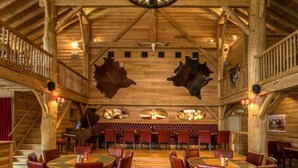 A rustic wooden interior with high ceilings, leather booths, and a grand piano.