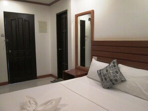 A hotel room with a bed, a nightstand, a mirror, and two doors.