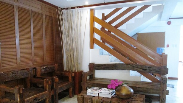 A wooden bench with a vase and magazines, a wooden table, and a staircase with wooden railings.