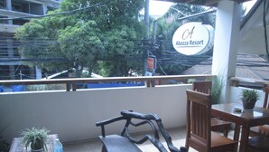A balcony with a wooden bench, a table with a potted plant, and a sign for Abozza Resort.