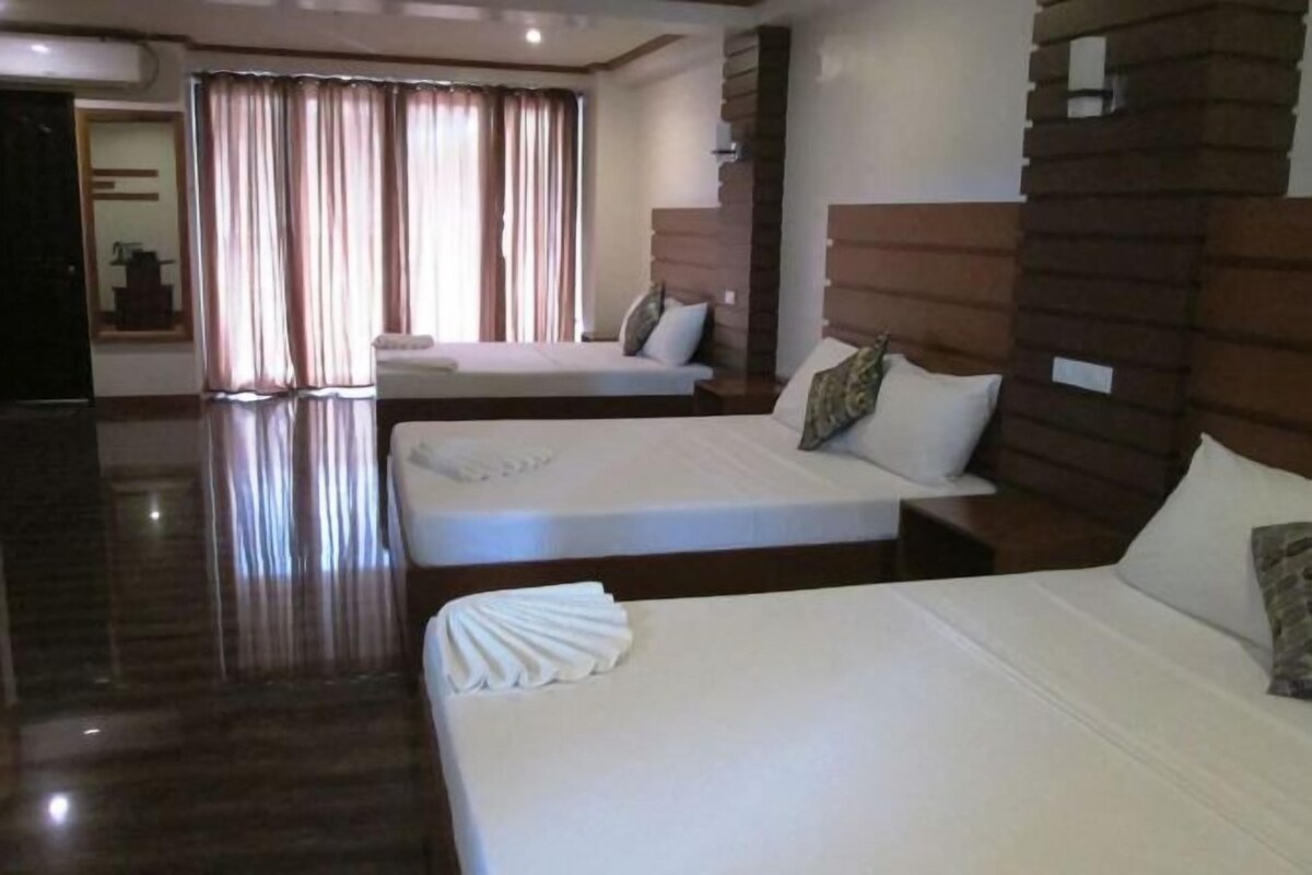 A hotel room with two beds, a wooden headboard, and a large window with curtains.