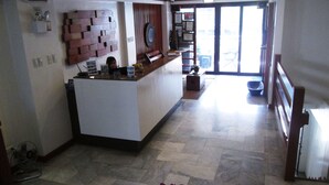 A reception area with a counter, a wall-mounted clock, and a potted plant.