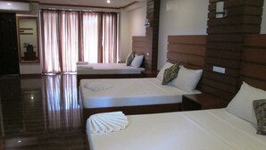A hotel room with two beds, a wooden headboard, and a large window with curtains.