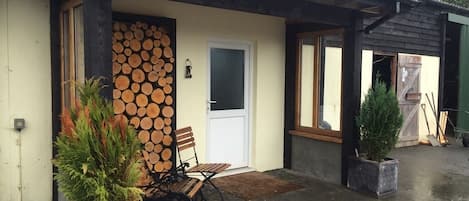 Un bâtiment rustique avec une façade en bois, une porte, un banc et une plante en pot.