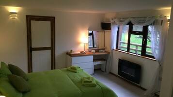 A bedroom with a bed, a desk, a TV, and a window with curtains.