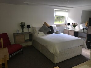 A bedroom with a bed, a desk, a chair, a nightstand, and a window. - Barton Gate Farm Guesthouse (Holsworthy)