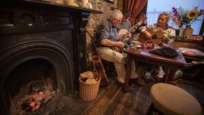 A cozy room with a fireplace, wooden furniture, and a table with musical instruments. - The Rostrevor Inn (Newry)