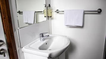 A bathroom with a white sink, a mirror, and two towels hanging on a towel bar.