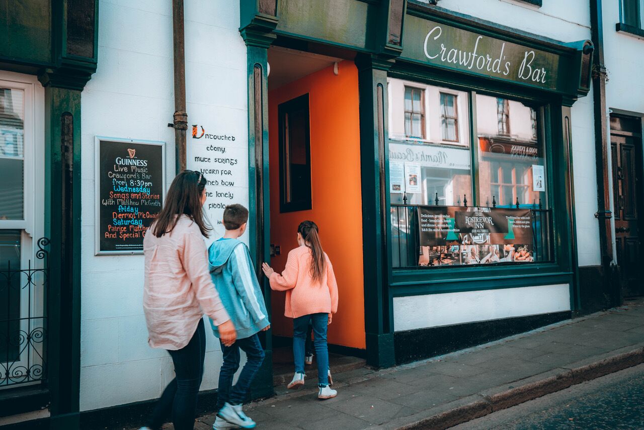 A storefront with a sign for 'Crawford's Bar' and a menu board advertising Guinness Live Music events.