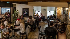 A restaurant with wooden beams, tables, and chairs. There are people dining and a sign on the wall. - The Rostrevor Inn (Newry)