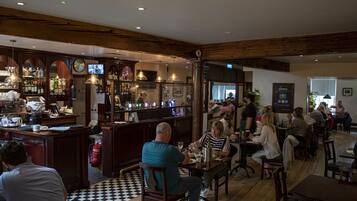 A restaurant with wooden beams, a bar area, and patrons dining.