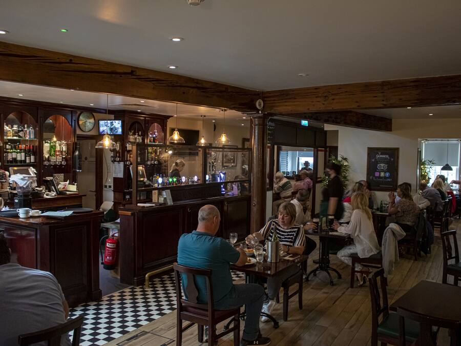 A restaurant with wooden beams, a bar area, and patrons dining.