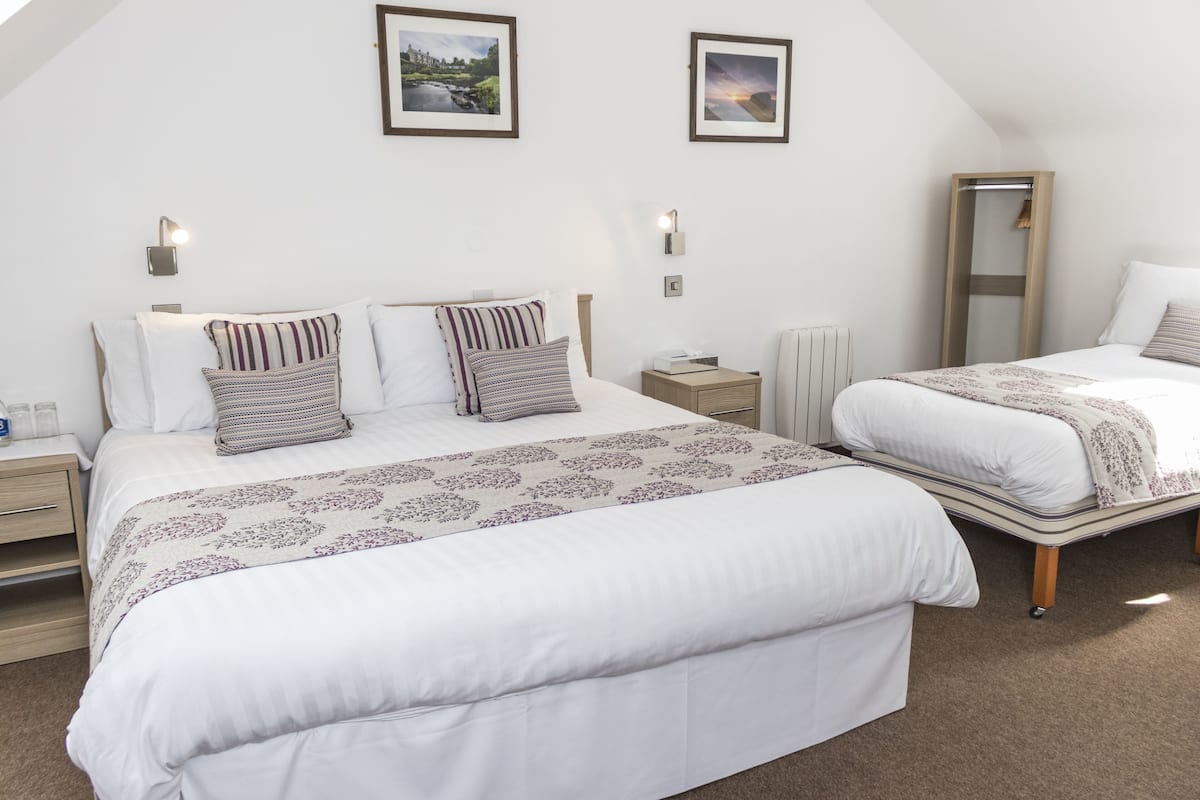 A bedroom with two beds, a large mirror, and two wall-mounted lights.