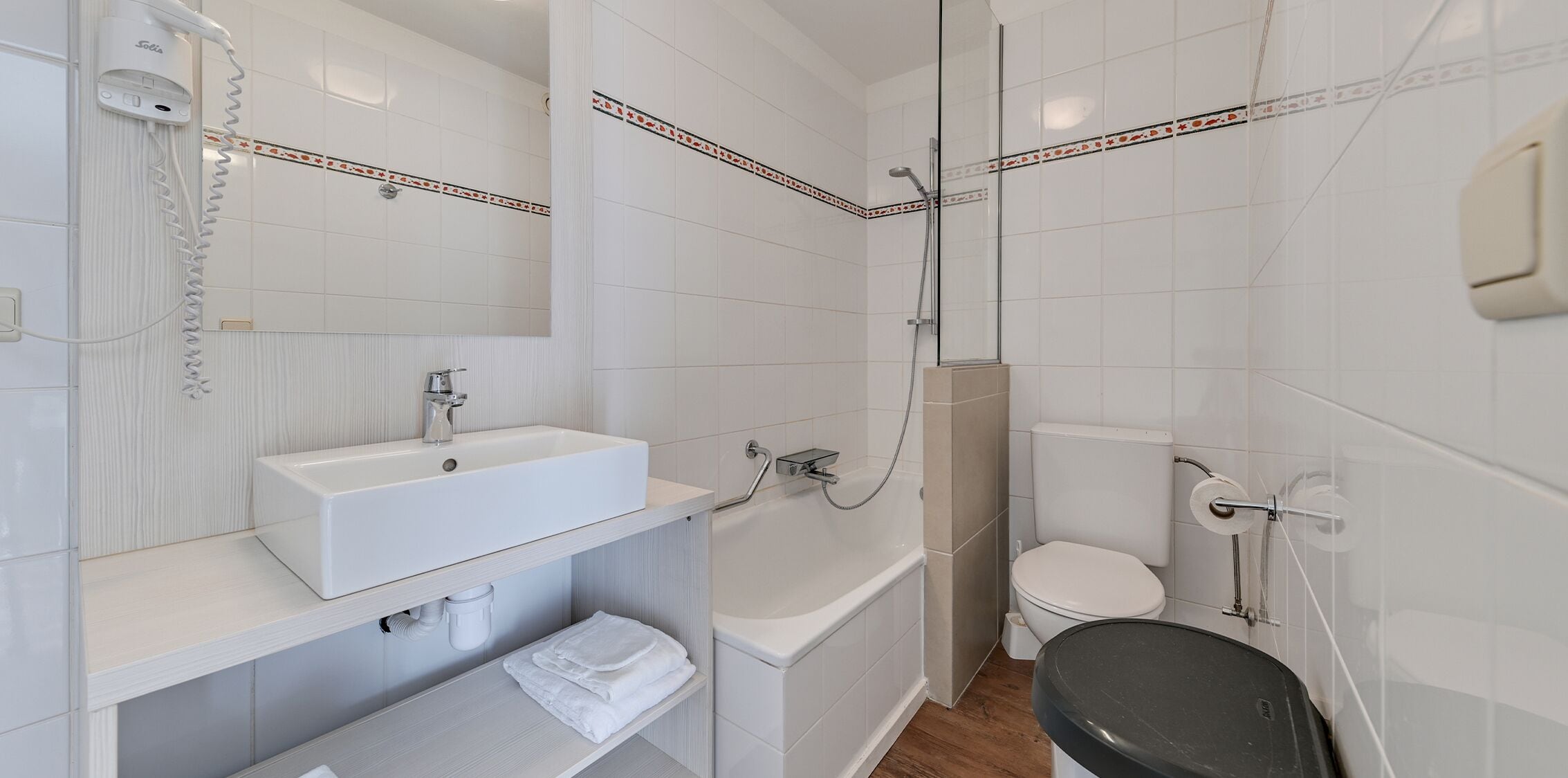 Une salle de bain moderne avec un lavabo blanc, un miroir et des toilettes.