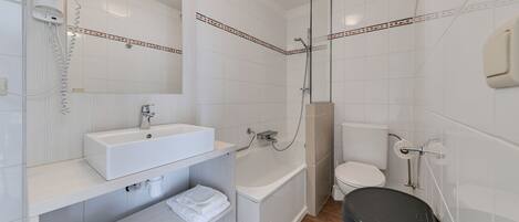 A modern bathroom with a white sink, mirror, and toilet.