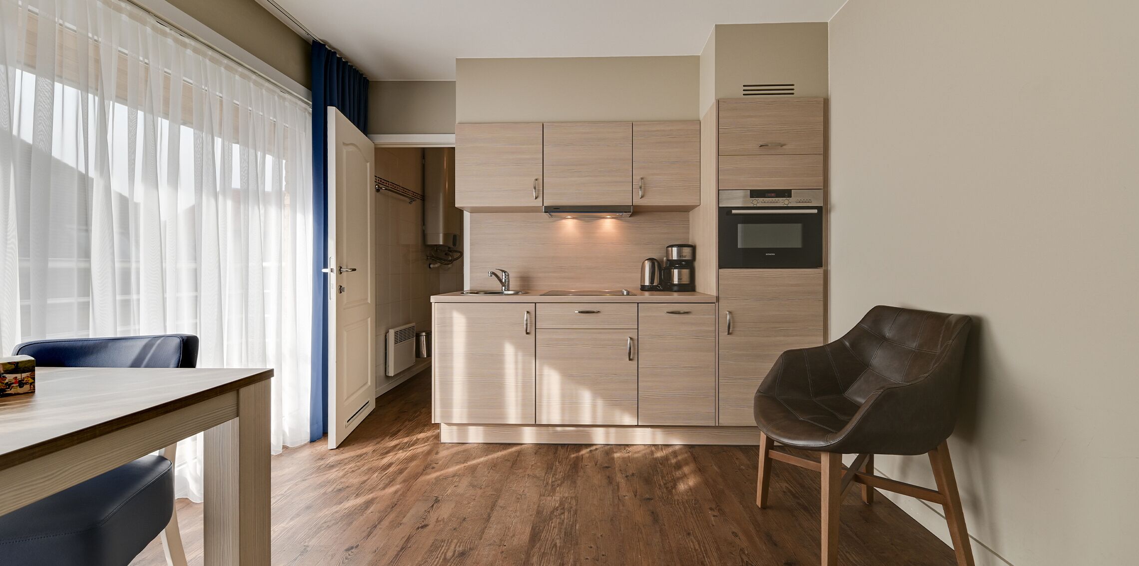 Eine moderne Küche mit hellen Holzschränken, einem eingebauten Ofen und einer Kaffeemaschine.