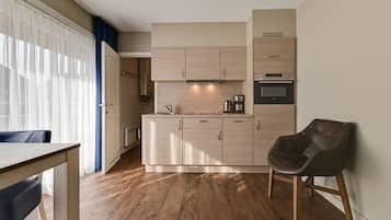 Eine moderne Küche mit hellen Holzschränken, einem eingebauten Ofen und einer Kaffeemaschine.