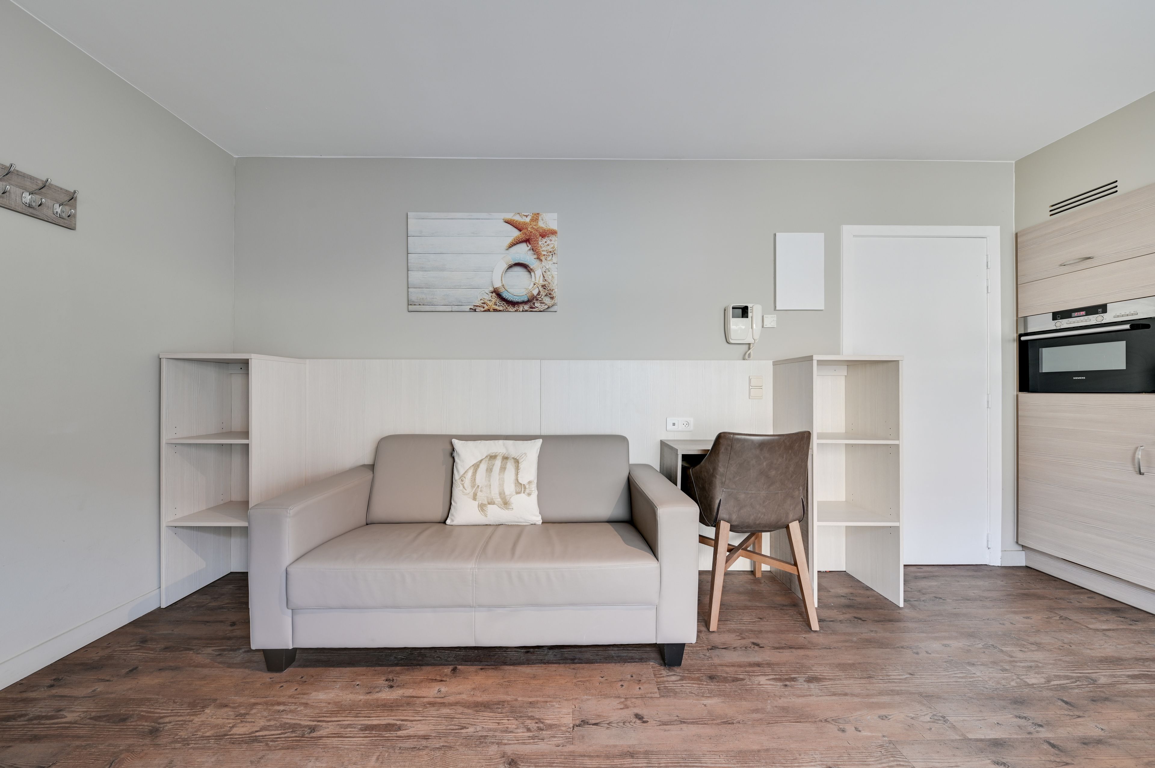 Una sala de estar moderna con un sofá, una silla y una zona de cocina con estufa.