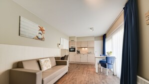 A modern living room with a sofa and a dining area with chairs and a table. - Holiday Suites De Haan (De Haan)
