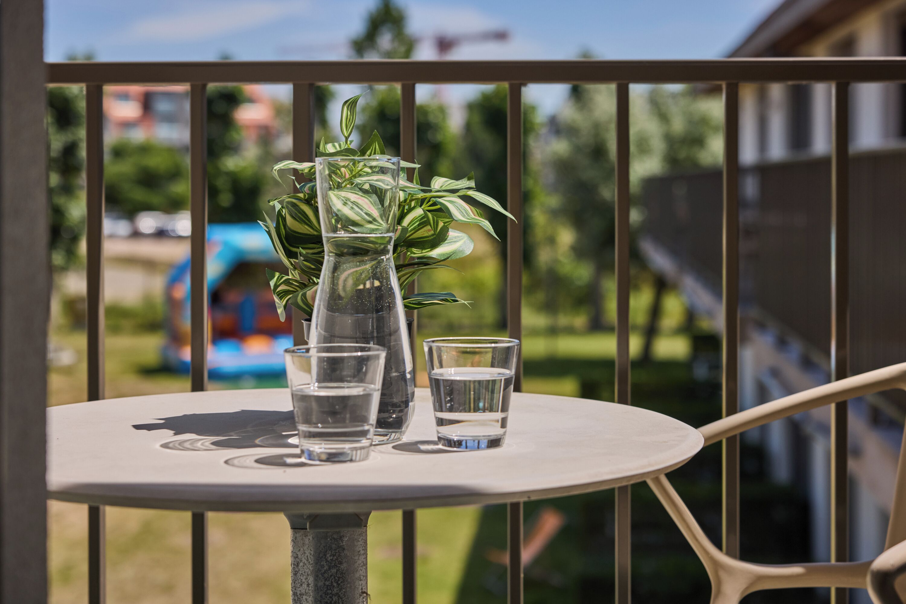 Une table avec un vase et deux verres sur un balcon.