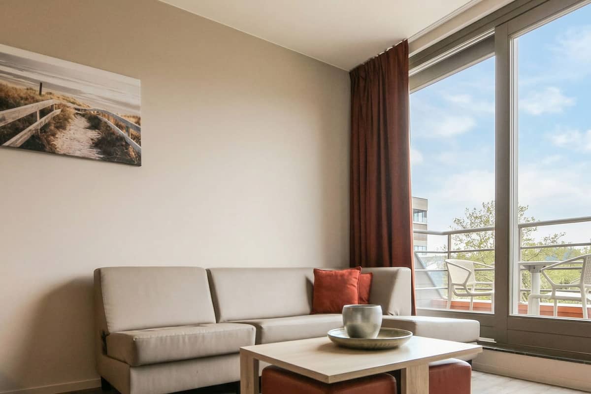 Une pièce moderne avec un canapé, un pouf et une table sur laquelle se trouve un bol.