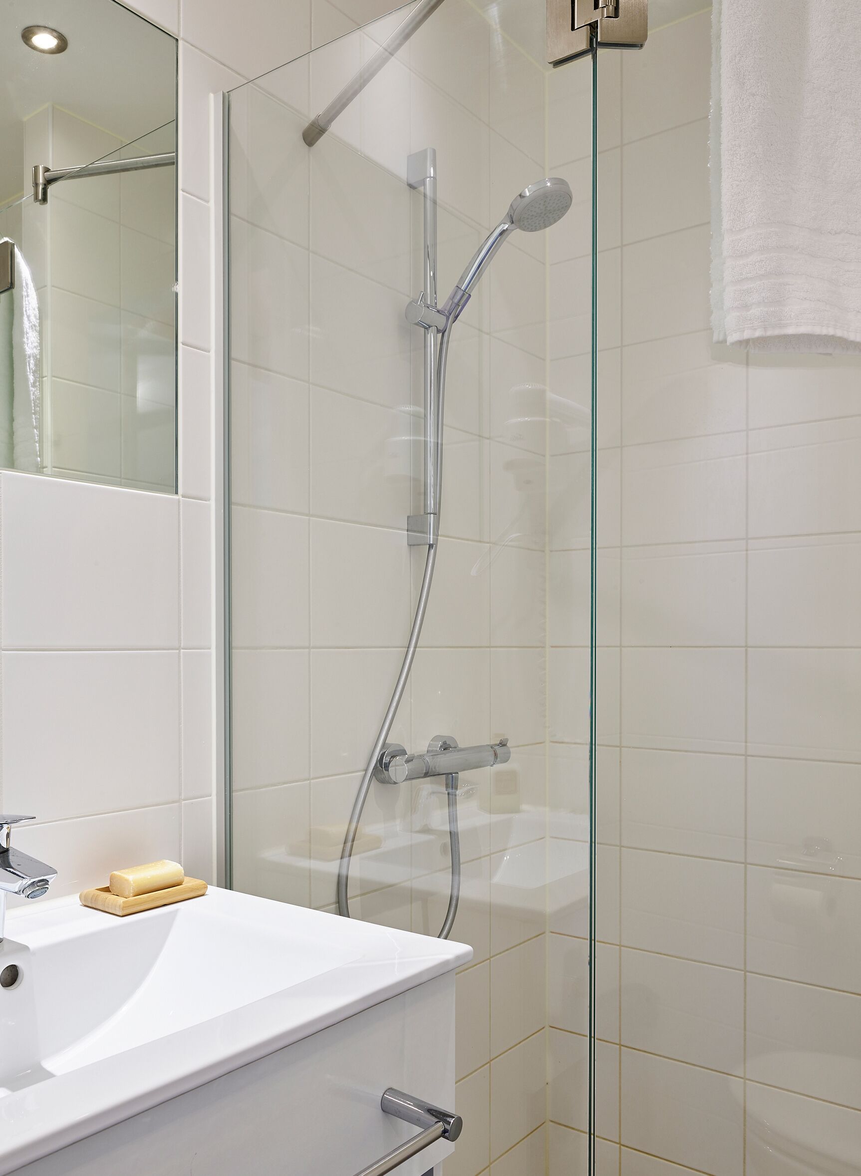 Une salle de bain moderne avec une douche à parois de verre, un lavabo blanc et un miroir.